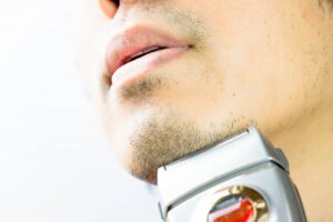 電気シェーバーで髭を剃っている男性