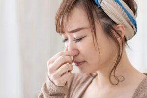鼻をつまむ女性